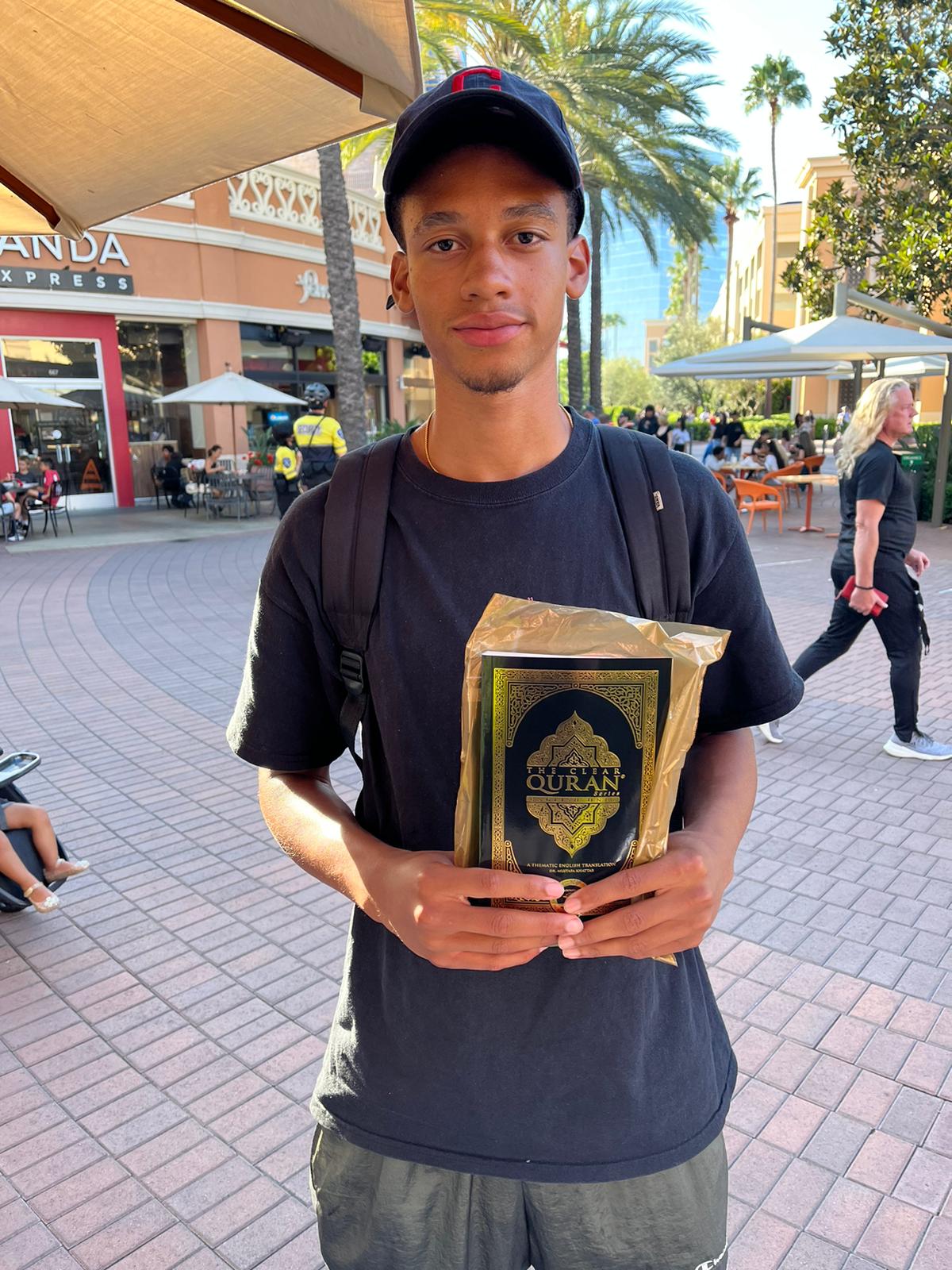 Young man holding a copy of The Clear Quran